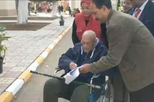 قاض يخرج لناخب من ذوى الاحتياجات الخاصة أمام مقر اللجنة ليدلى بصوته